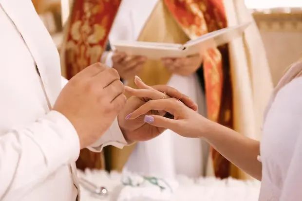 Hai chiếc nhẫn cưới đặt gần sách Kinh Thánh, ánh sáng ấm