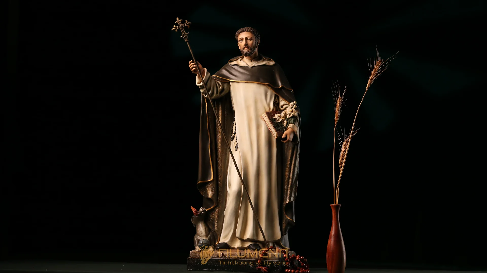 Thánh Đa Minh trong tu phục trắng đen, tay cầm Kinh Thánh và nhành huệ.