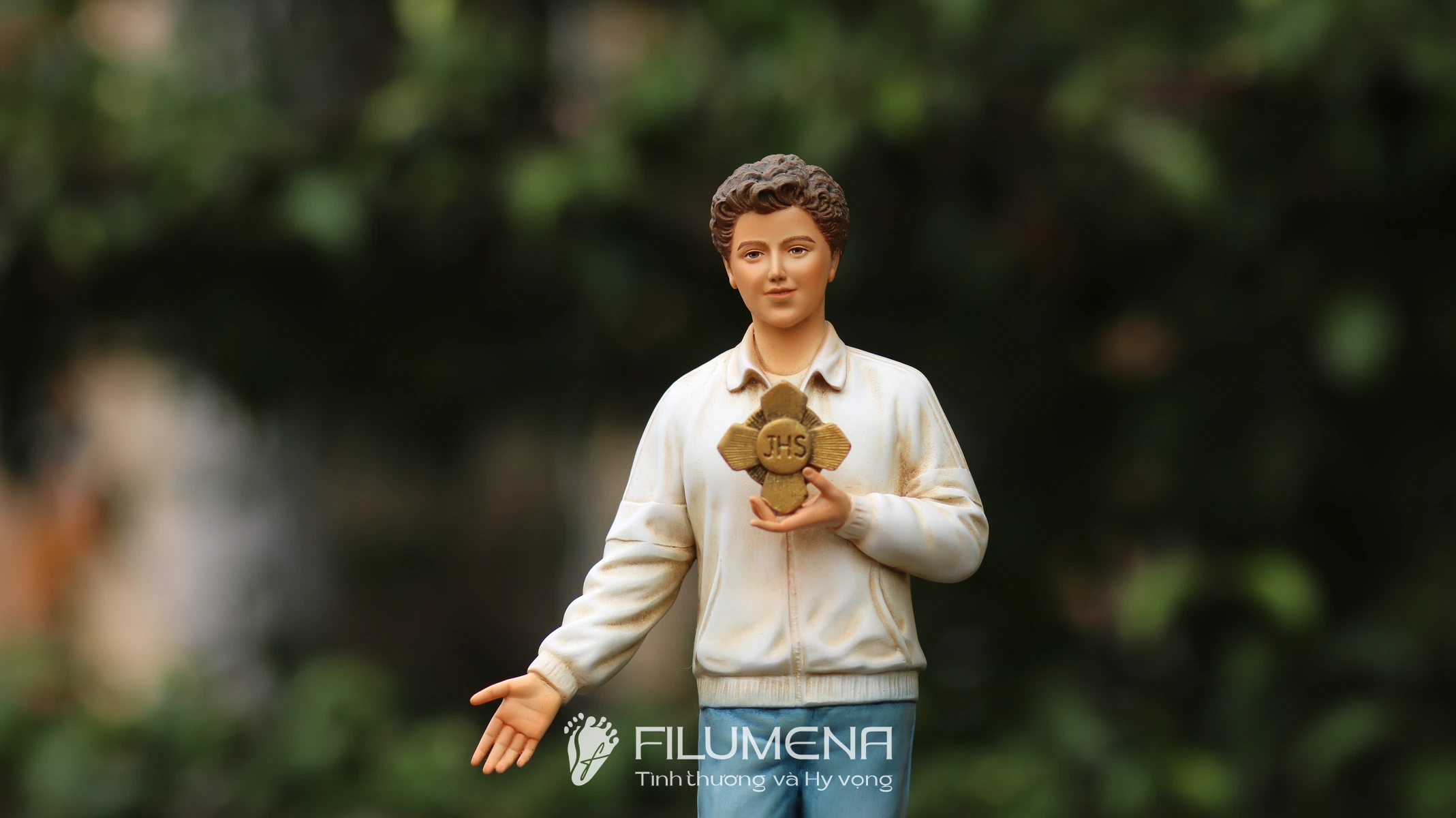 Hình ảnh tượng Thánh Carlo Acutis do Filumena sáng tác: quần jean và áo khoác sáng màu trẻ trung.